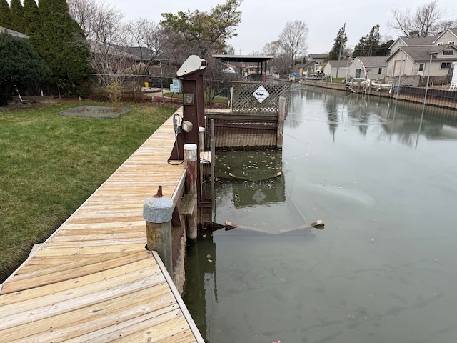 view of dock with a lawn and a water view