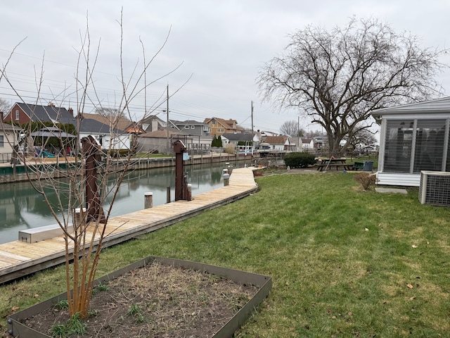 view of yard with a water view, a dock, and cooling unit