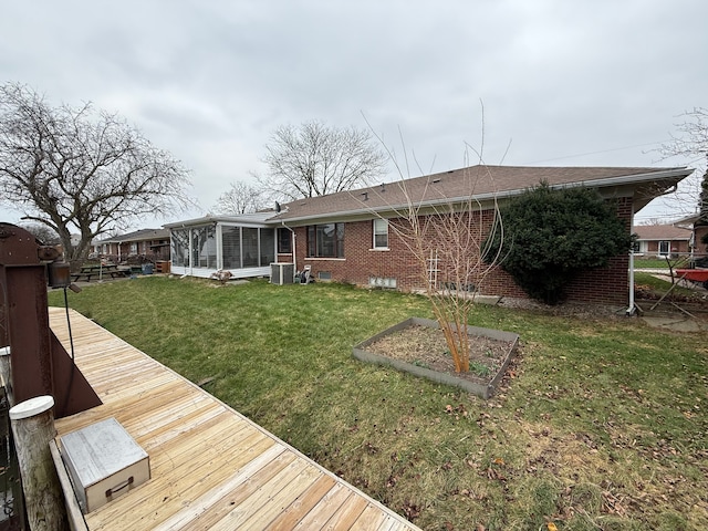 back of house featuring a lawn, a sunroom, and central AC unit