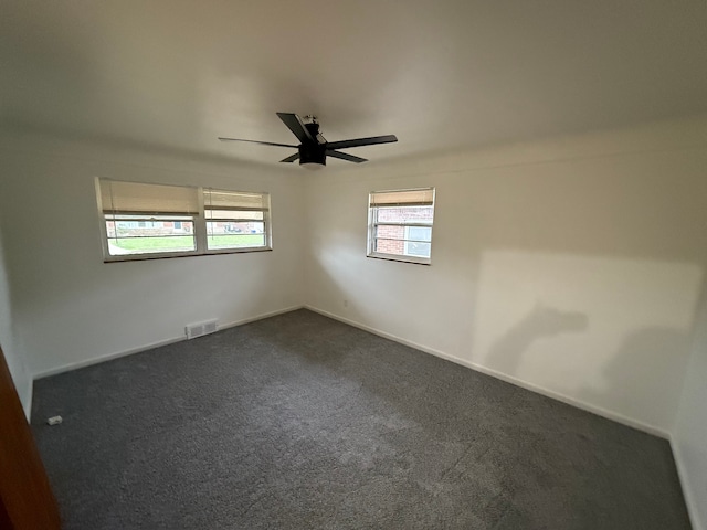 empty room featuring ceiling fan and dark carpet