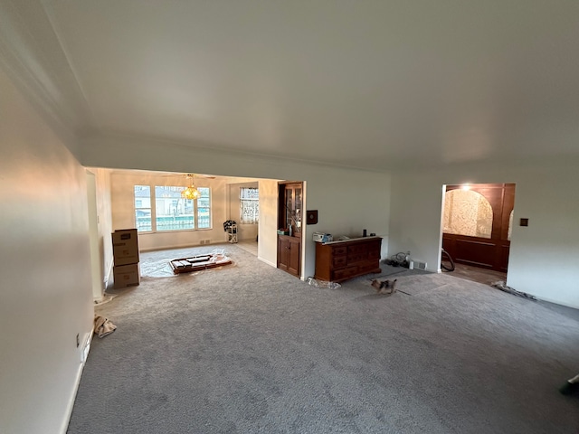 unfurnished living room featuring an inviting chandelier and light colored carpet