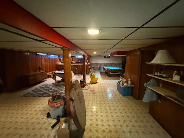 basement featuring a drop ceiling, wood walls, and billiards