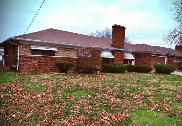 exterior space with brick siding, a yard, a chimney, and an attached garage