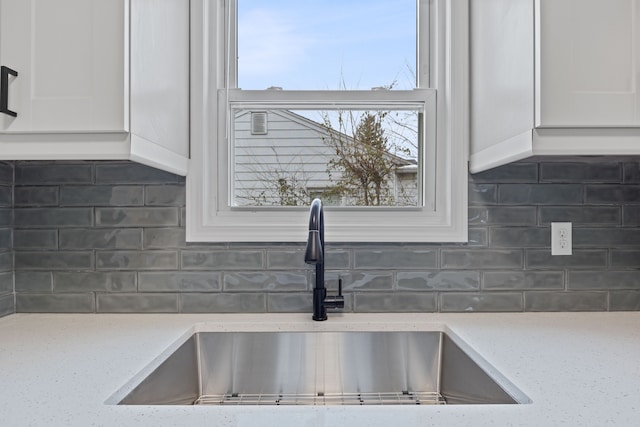 details featuring light stone countertops, tasteful backsplash, and sink