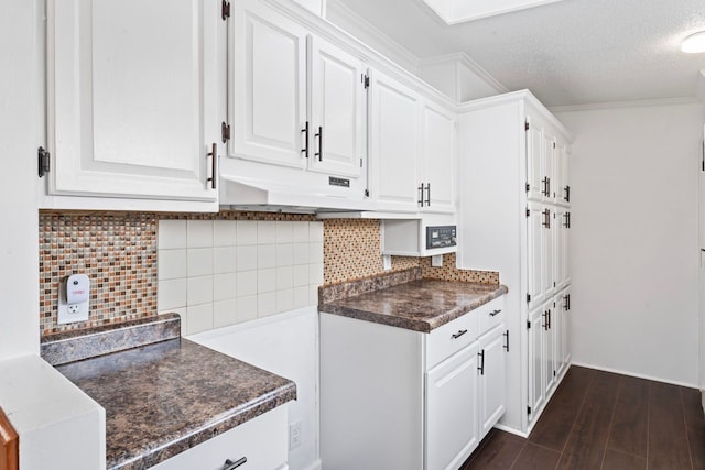 kitchen featuring backsplash, dark wood-type flooring, white cabinets, crown molding, and a textured ceiling