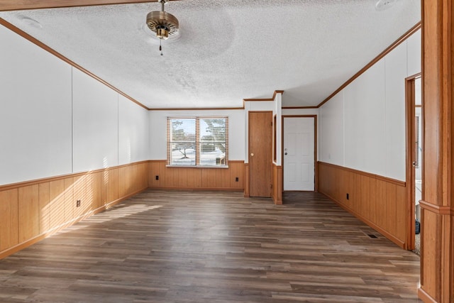 spare room featuring dark wood-type flooring, a textured ceiling, and ornamental molding