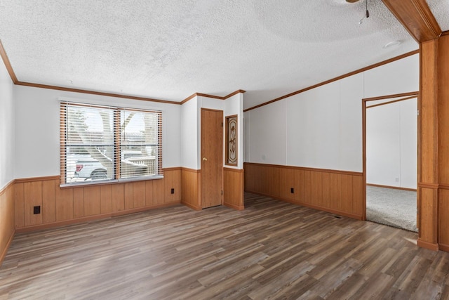 unfurnished room with hardwood / wood-style floors, crown molding, a textured ceiling, and wooden walls