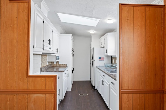 kitchen featuring a textured ceiling, a skylight, white cabinetry, and dark hardwood / wood-style floors