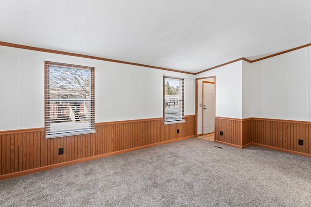 unfurnished room featuring wood walls, ornamental molding, a textured ceiling, and light carpet