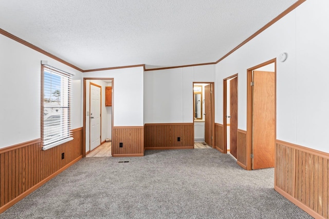 unfurnished room featuring wood walls, light colored carpet, and a textured ceiling