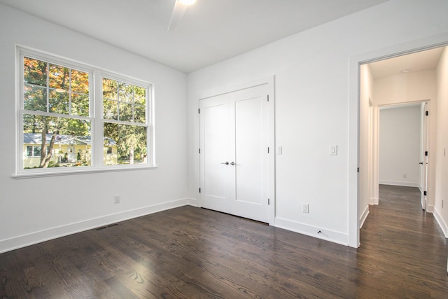 unfurnished bedroom with dark hardwood / wood-style floors, ceiling fan, and a closet