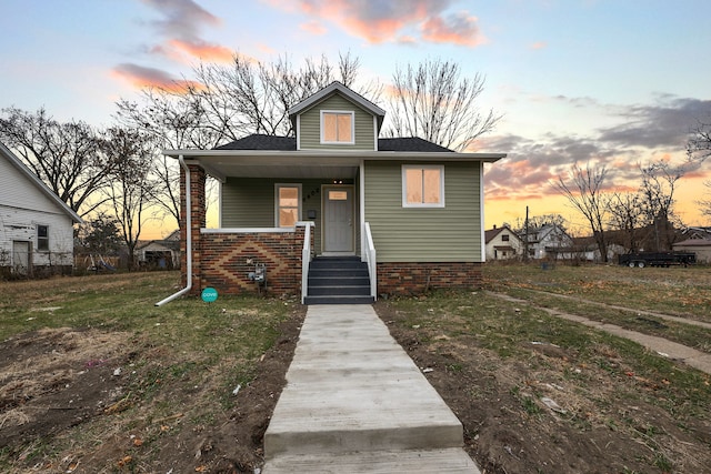 bungalow featuring a porch and a yard