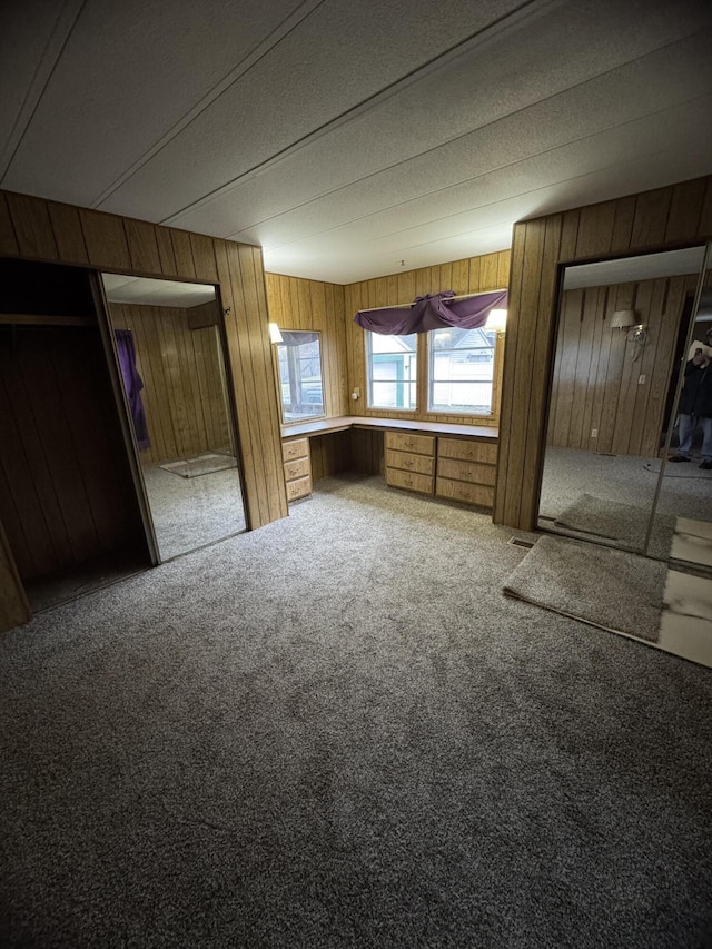 unfurnished bedroom featuring carpet flooring and wooden walls