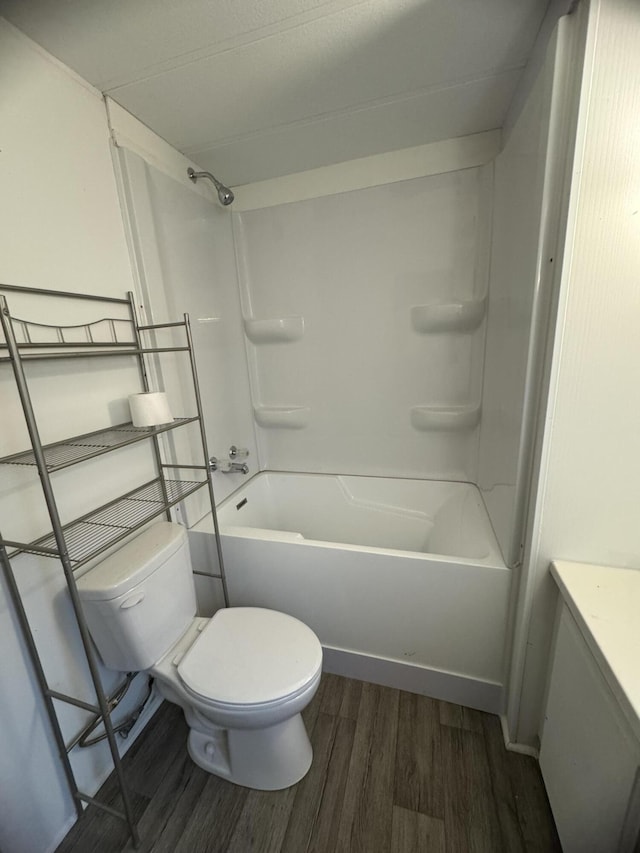 bathroom with hardwood / wood-style floors, washtub / shower combination, and toilet