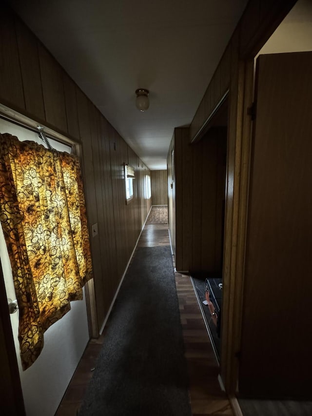 hallway featuring dark hardwood / wood-style floors and wooden walls