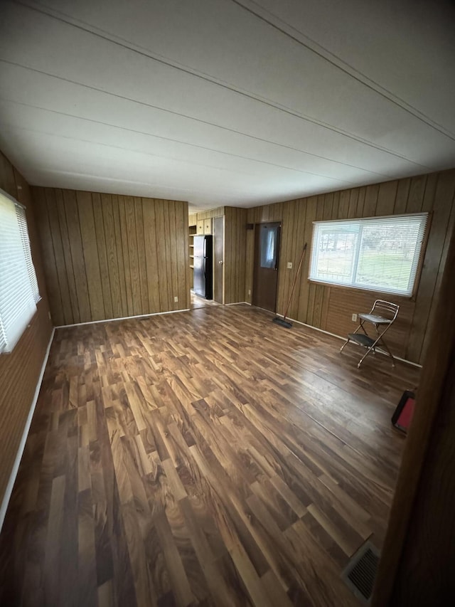 unfurnished room with wood walls and dark hardwood / wood-style flooring