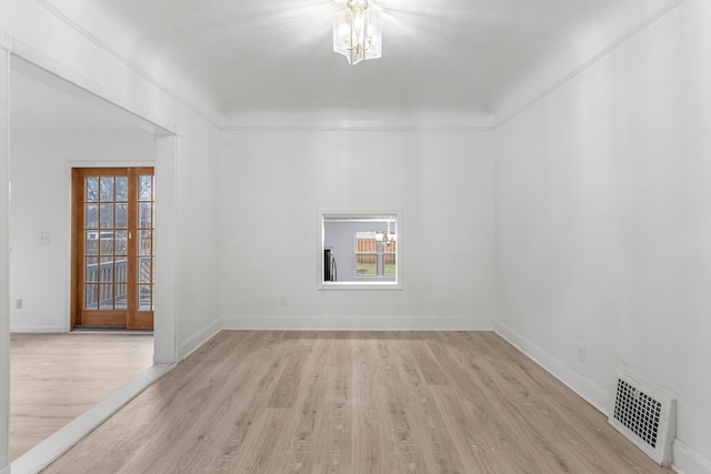 empty room with a notable chandelier and light wood-type flooring