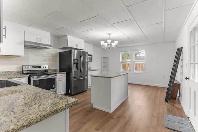 kitchen with hardwood / wood-style floors, light stone countertops, appliances with stainless steel finishes, a kitchen island, and white cabinetry