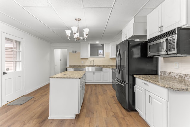 kitchen featuring decorative backsplash, stainless steel appliances, sink, a center island, and white cabinetry