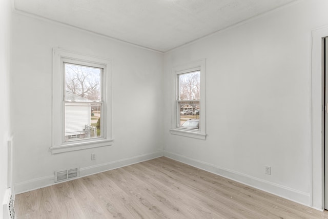 empty room featuring light hardwood / wood-style flooring, a wealth of natural light, and a baseboard heating unit