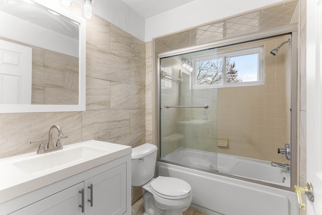 full bathroom featuring tasteful backsplash, vanity, shower / bath combination with glass door, tile walls, and toilet