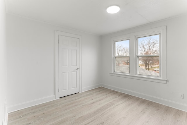 spare room with light wood-type flooring and crown molding