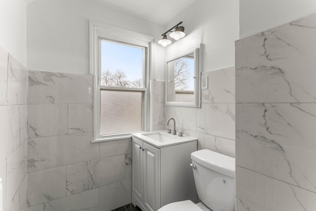 bathroom featuring vanity, toilet, and tile walls