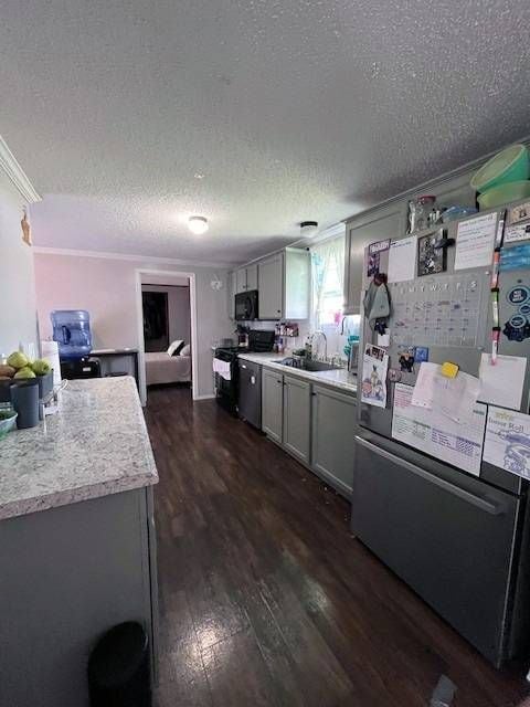 kitchen with gray cabinets, dark hardwood / wood-style flooring, a textured ceiling, and appliances with stainless steel finishes