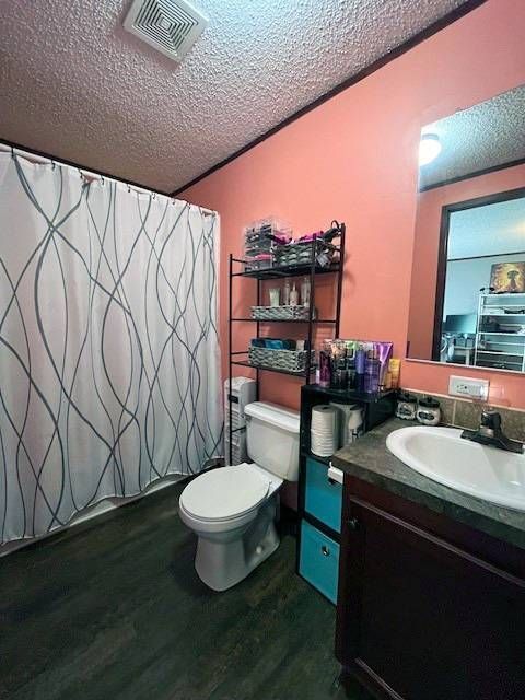 bathroom featuring hardwood / wood-style floors, vanity, a textured ceiling, and toilet