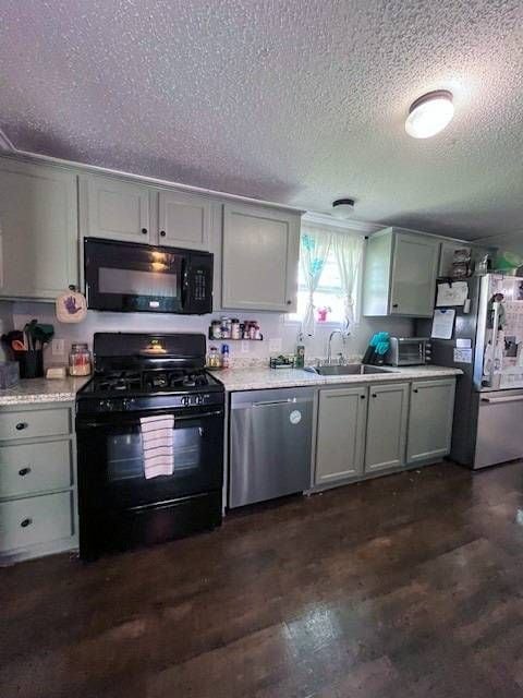 kitchen featuring a textured ceiling, sink, dark hardwood / wood-style flooring, and black appliances