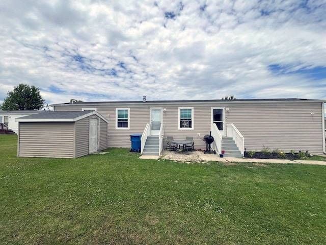 rear view of house with a storage unit, a yard, and a patio