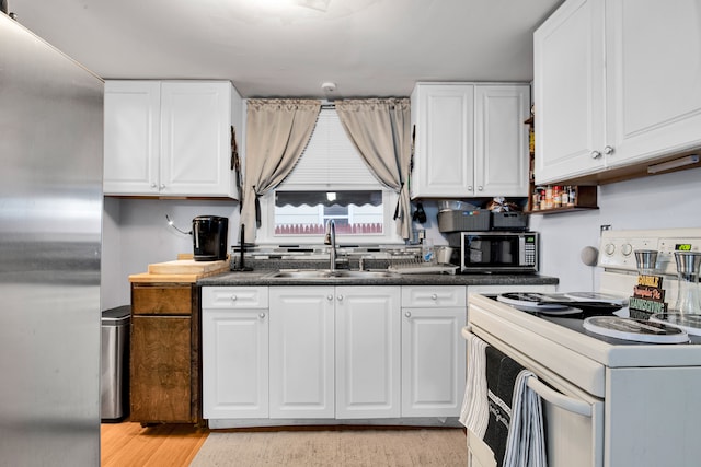 kitchen with white cabinets, appliances with stainless steel finishes, light wood-type flooring, and sink