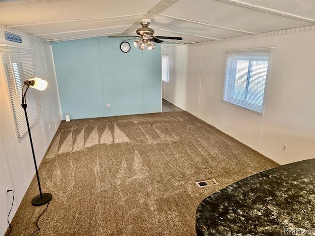 unfurnished room featuring carpet, ceiling fan, and beamed ceiling