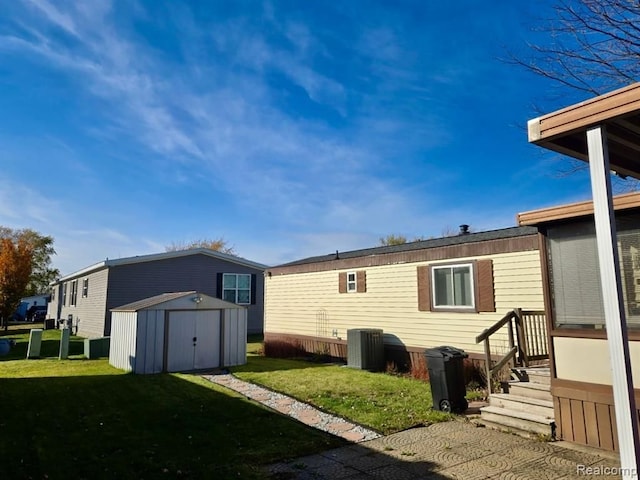 back of house featuring a storage unit, cooling unit, and a lawn