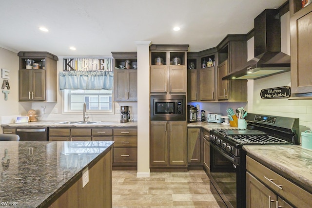 kitchen featuring sink, wall chimney exhaust hood, stainless steel appliances, backsplash, and dark stone counters