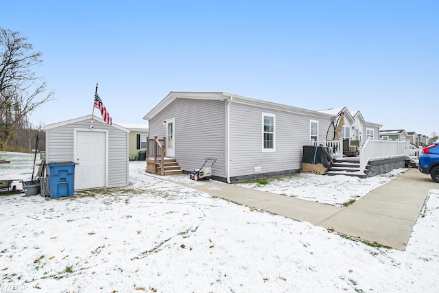 snow covered property with a storage shed and a deck