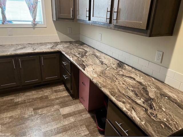 kitchen featuring light stone countertops, dark brown cabinets, and dark hardwood / wood-style flooring