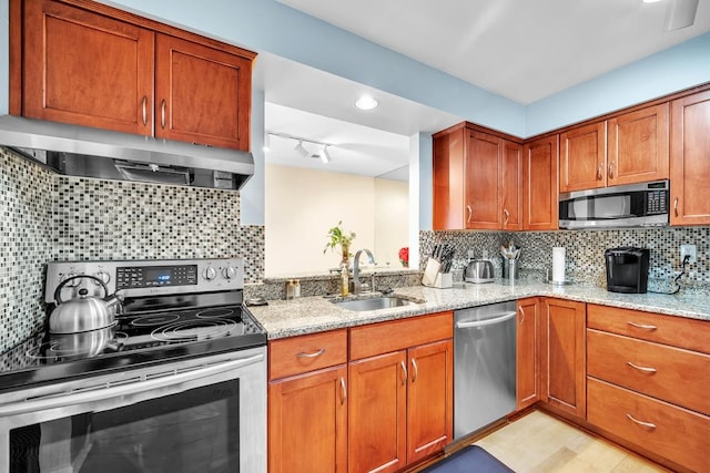 kitchen featuring backsplash, light stone countertops, sink, and appliances with stainless steel finishes