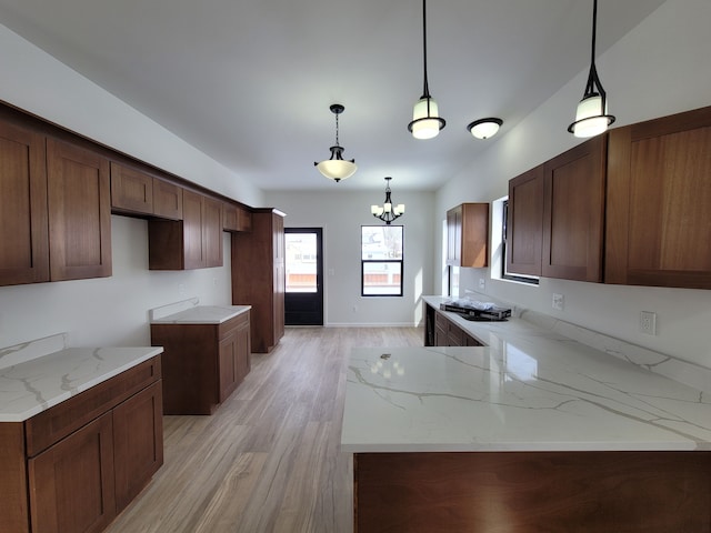 kitchen with hanging light fixtures, light stone countertops, and light hardwood / wood-style floors