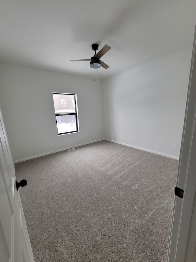 carpeted empty room with baseboards, visible vents, and ceiling fan