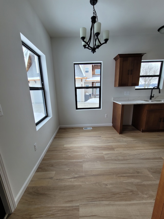 kitchen featuring light wood-style flooring, a sink, visible vents, light countertops, and hanging light fixtures