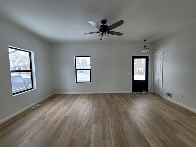 empty room featuring light wood-style floors, baseboards, visible vents, and a ceiling fan