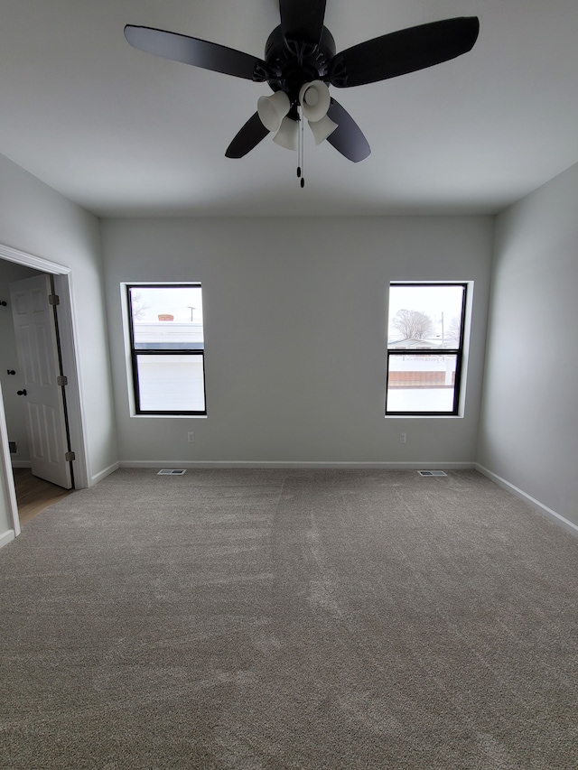 unfurnished room featuring visible vents, plenty of natural light, and carpet flooring