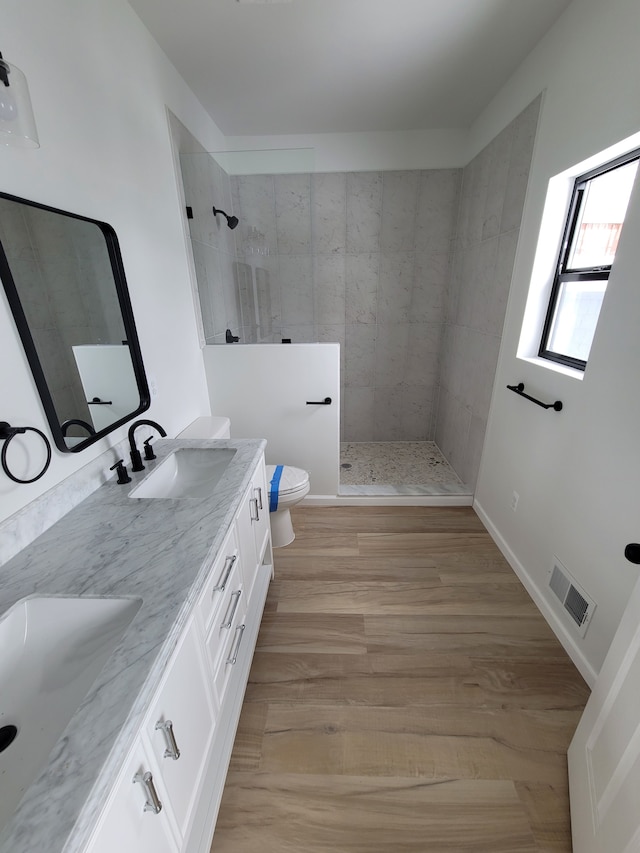 full bathroom with double vanity, visible vents, toilet, walk in shower, and a sink