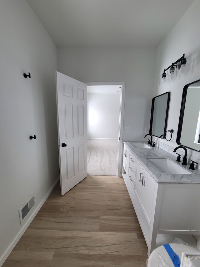 full bathroom with wood finished floors, visible vents, a sink, and double vanity