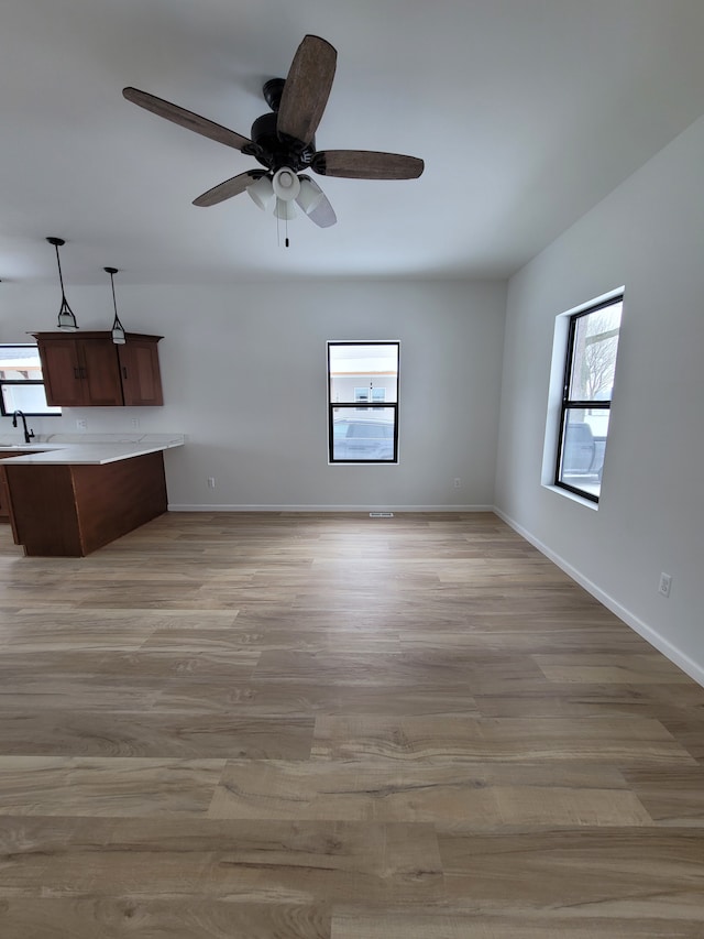 unfurnished living room with baseboards, a sink, and light wood finished floors