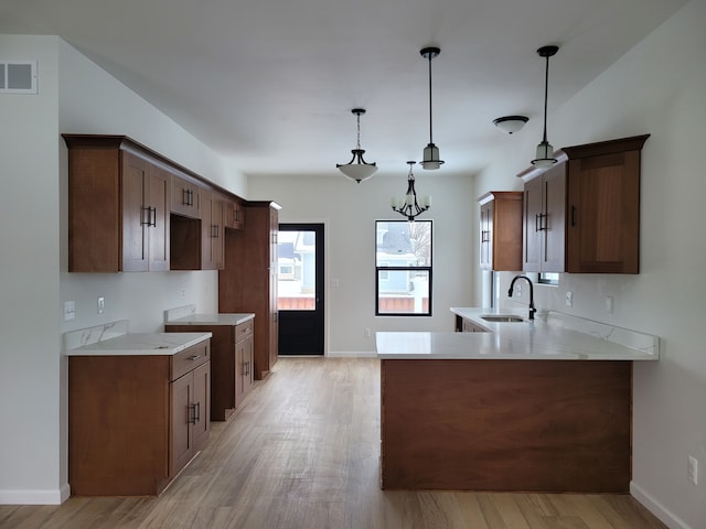 kitchen featuring pendant lighting, light countertops, a sink, and visible vents