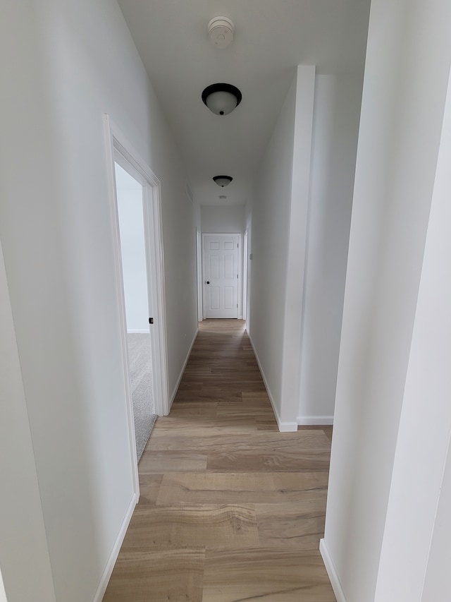 hallway featuring light wood-style floors and baseboards