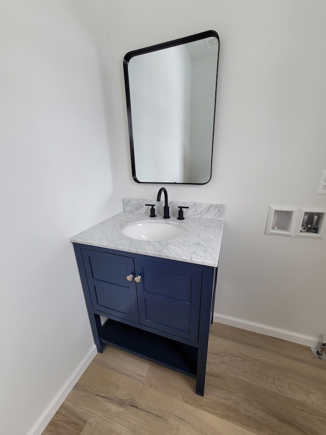 bathroom featuring vanity, baseboards, and wood finished floors