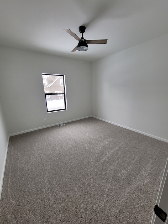 carpeted empty room featuring a ceiling fan, visible vents, and baseboards